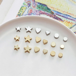 Close-up of assorted gold and silver star, heart, and circle DIY jewelry making charms