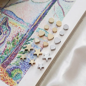 Macro detail of star, heart, and round DIY jewelry beads in gold and silver finishes