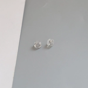 Close-up of clear silicone earring backings with invisible gold-plated earring stopper base