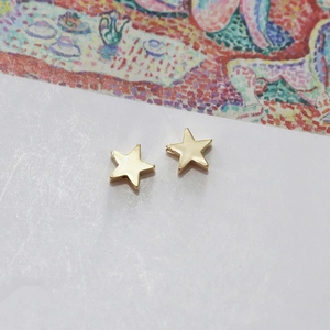 Detailed view of polished 14k gold plated star earrings on a white display base