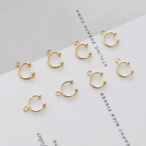 Macro view of eight gold plated C-shaped ear clips with small connecting loops for DIY jewelry