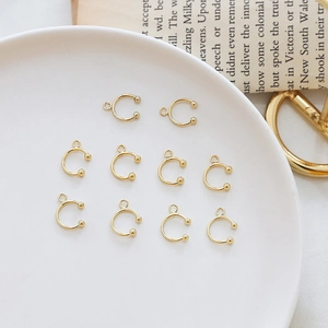 Detailed view of 10 gold plated C-shaped ear cuffs for DIY jewelry making on white tray