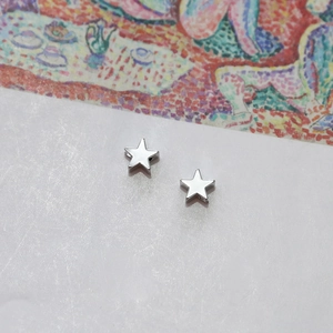 Macro shot of silver star-shaped stud earrings with polished finish on white background