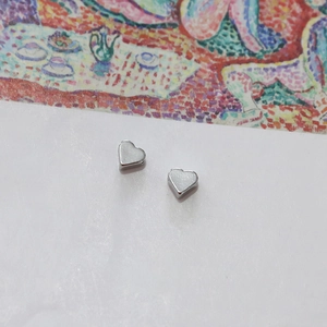 Detail of heart-shaped silver earrings with white glitter inlay on an artistic background