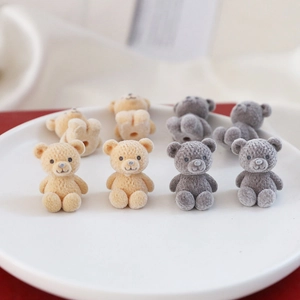 Close-up of cute flocked teddy bear charms in beige and grey for DIY jewelry making