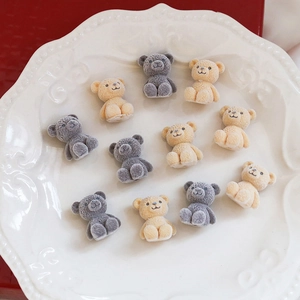 Macro shot of 11 cute flocked teddy bear charms for DIY crafts in grey and beige colors