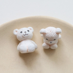 Detailed close-up of white flocked teddy bear charms for DIY jewelry and crafts