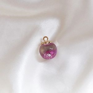 Detailed macro view of a glass sphere pendant with pink dried flowers and a gold metal cap