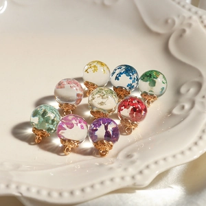 Transparent glass orb charms filled with colorful dried flowers and golden metal caps