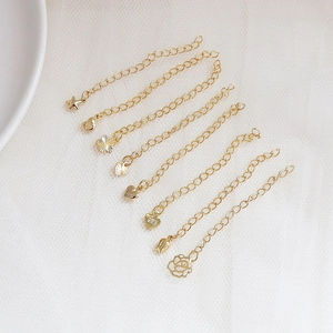 Close-up of 14k gold-plated jewelry extension chains with heart and flower charms
