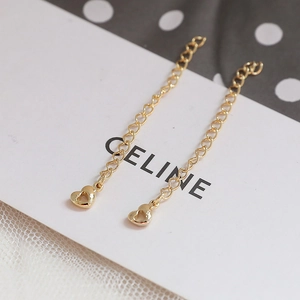 Macro shot of 14k gold plated chain earrings with heart pendants on a white card