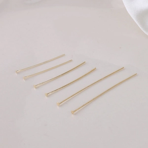 Detailed macro view of 14k gold plated flat head pins in various lengths for DIY jewelry