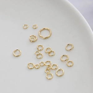 Anellini aperti placcati in oro per gioielli fai-da-te su piatto di porcellana bianca