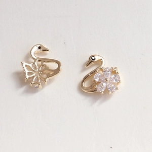 Detailed close-up of golden swan nail charms with sparkling rhinestones and flower pattern