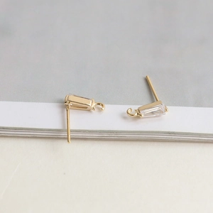 Gros plan sur clous d'oreilles dorés avec zircon rectangulaire pour création de bijoux