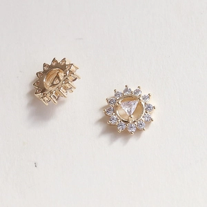Macro detail of golden sunflower stud earrings with zircon inlay and sparkling crystals