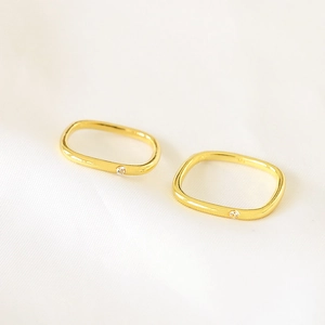 Detailed macro view of two gold-plated rectangular rings with small cubic zirconia stones