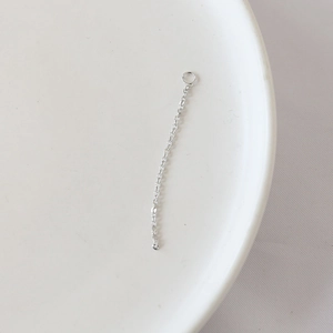 Macro shot of silver metal jewelry extension chain with fine link structure on white tray