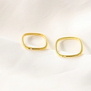 Minimalist gold plated square ring with sparkling diamond accent on textured white fabric