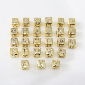 Vista macro di 26 perle dorate con lettere e zirconi per bracciali gioielli DIY