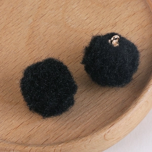 Detail of soft black plush pompom charms with gold metal rings for DIY jewelry making
