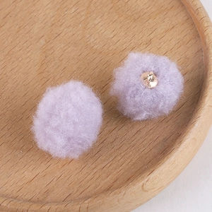 Close-up of soft lavender plush pompom balls with golden metal loops for DIY jewelry making