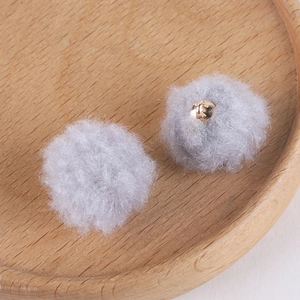 Macro view of grey fluffy pom-pom beads with gold metal accents for DIY jewelry making