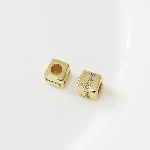 Macro di una perla a cubo dorata con lettera J in zircone per gioielli fai-da-te