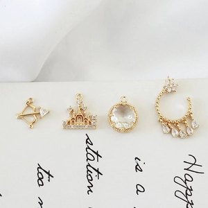 Macro view of four gold-plated vintage charms including castle and arrow designs with zircons