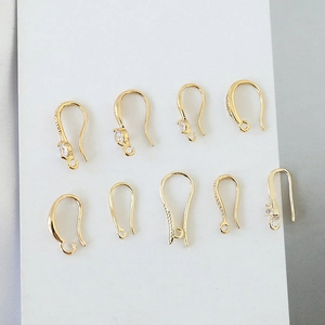 Detalle de ganchos de pendientes chapados en oro 18k con circonitas y pequeños colgantes