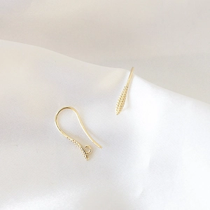 Detalle de ganchos para pendientes chapados en oro 18k con circón en seda blanca