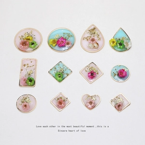 Macro view of geometric resin pendants featuring real dried flowers and gold leaf details