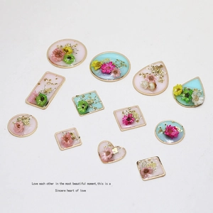 Flat lay of geometric gold resin pendants with real dried flowers and gold foil for DIY