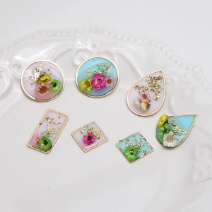 Detailed view of dried flower resin pendants with gold foil in geometric metal frames