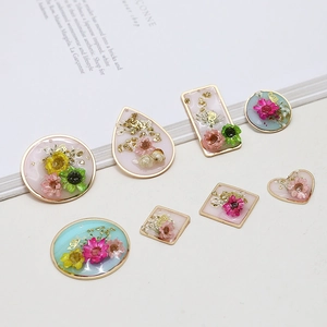 Macro shot of resin pendants with real dried flowers and gold foil in gold metal frames