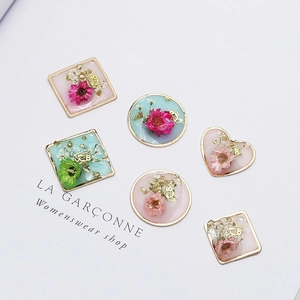 Macro shot of geometric resin pendants with real dried flowers and gold leaf foil details
