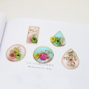 Detailed view of handmade resin pendants with real dried flowers and gold metal frames