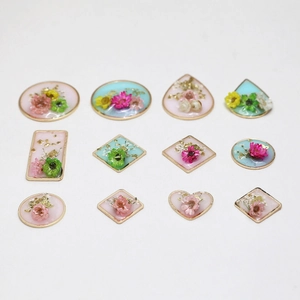 Detailed view of resin jewelry pendants with dried flowers and gold leaf in gold frames