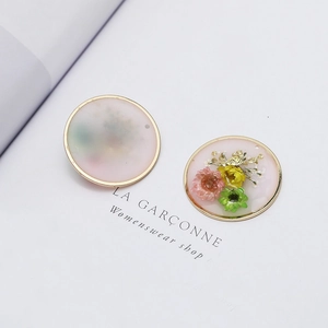 Detail of round resin flower pendant with gold edges and dried floral inclusions