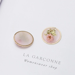Close-up of circular resin charms with pink dried flowers, gold foil, and butterfly inlay