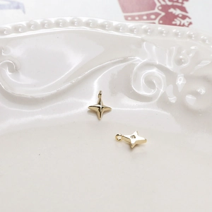 Detailansicht der hellgoldenen vierzackigen Sternanhänger auf Keramik für DIY-Schmuck