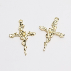 Vue macro de pendentifs croix avec rose en métal doré et détails de pétales gaufrés