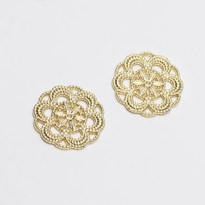 Vue macro détaillée de deux breloques dorées en forme de fleurs creuses avec motifs fins