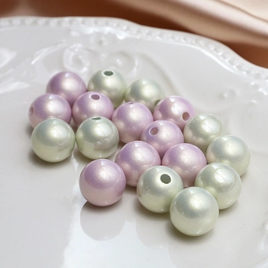 Perle in resina color lavanda e verde acqua su piatto bianco per creazione gioielli