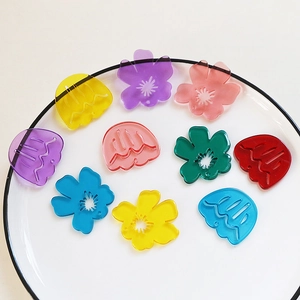 Detailed view of colorful acrylic flower pendants for DIY jewelry crafting on white plate