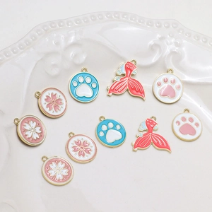 Detailed view of DIY alloy charms with floral and paw designs on a ceramic tray