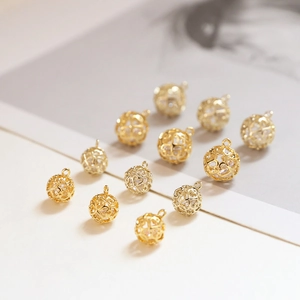 Dettaglio di ciondoli a sfera traforati placcati oro 18k con motivi a cuore per DIY