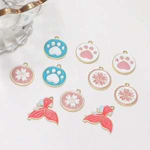 Detailed macro view of colorful alloy enamel paw, flower, and mermaid tail DIY charms