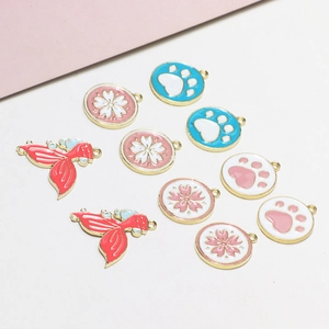 Detailed view of DIY alloy charms with cherry blossom, paw print, and fish tail enamel designs