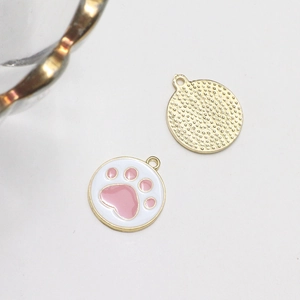 Detail of alloy charm showing pink paw print design with golden textured back for DIY jewelry